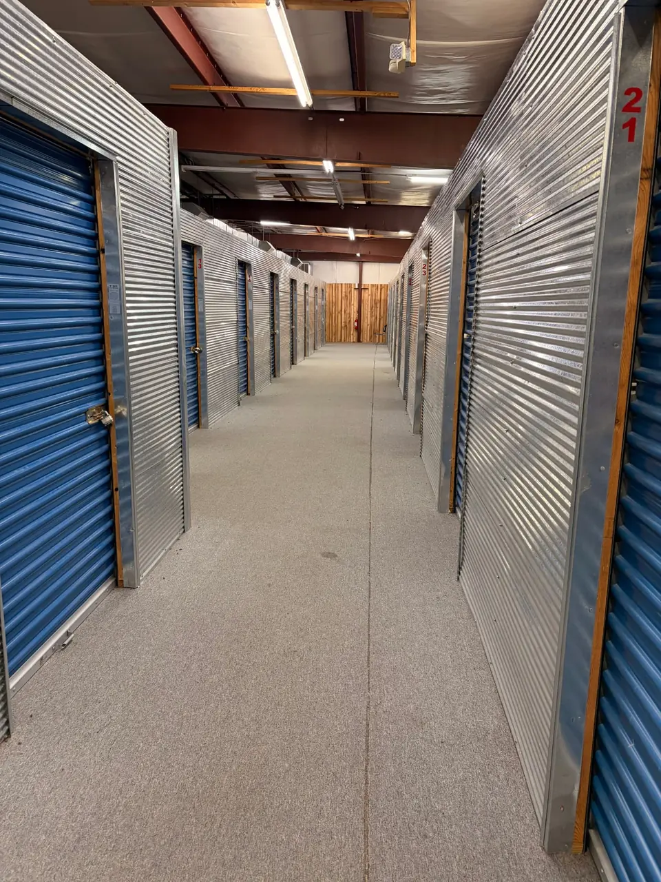 Climate-controlled indoor storage hallway with blue roll-up unit doors at American Mini Storage in Staunton, VA